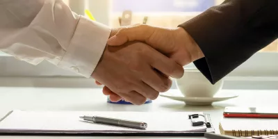 Two people shaking hands over a table.